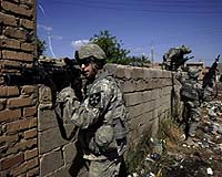 A US soldier from Baker Company 2-12 Infantry Battalion aims his weapon to provide security while his comrades jump over a concrete wall to take cover in their trucks after insurgents detonated an IED or Improvised Explosive Device, 20 metres from their position during a foot patrol through the streets of the predominantly Sunni al-Dora neighborhood of southern Baghdad, 18 March 2007. US Secretary of Defense Robert Gates said today it was too soon to know whether the recent 